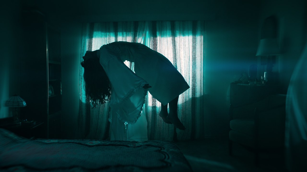 a woman in a white dress upside down in a room with curtains